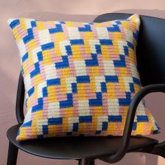 Ilmainen ohje, kuvituskuva: Molla Mills Blanki-tyyny. Nelivärikuvioinen virkattu koristetyyny tuolilla. Esito-huopalangasta sävyt valkaisematon, vaalea roosa, sininen ja vaaleankeltainen.