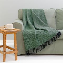 Lepohetki-huopa sohvalla. Huopa on kudottu Esito-huopalangasta sävyssä musta 7999 ja vihreä 7047.