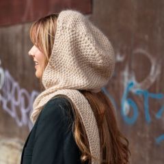 Tuisku-huppuhuivi naisen yllä huppu päässä. Huppuhuivi neulotaan Lankava Helli -merinolangasta värillä vaalea tammi 342 ja Austermann Kid Silk -langasta värillä hiekka 23.