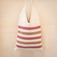 Free pattern: Essi Stripe Bag hanging on a wall. The striped bag is knitted with Lankava Essi Tube Yarn using colours natural white 2, dark rose 13 and light brown 4.