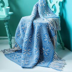 Free pattern: Leija Throw designed by Molla Mills on a chair. The throw is crocheted with Lankava Lysti sock yarn using colour Summer sky 857 and Naturelli Mahtava wool yarn using colour natural white.