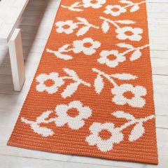 Saffron rug on the floor. The rug is crocheted with Lankava Pamela Macrame Cord using colours 58 burned orange and 52 natural white.