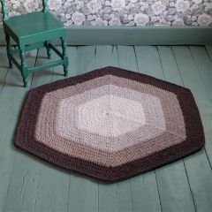 Free pattern Crocheted Sävy Rug on the floor next to a chair. The rug is crocheted with Lankava Frotee Loopy Craft Yarn using colours cocoa 55, linen beige 73, greige 87 and natural white 52.