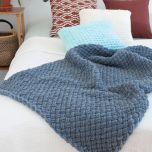 Pehmeä Alize Puffy-langasta sormineulottu torkkupeitto, väri 87 tummanharmaa.